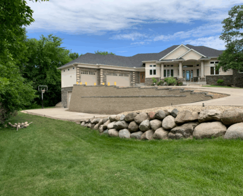 sloped block retaining wall and a boulder retaining wall surrounding residential driveway